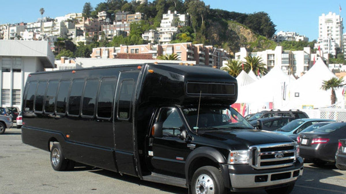 Black executive limo bus parked in San Francisco with Telegraph Hill houses behind it