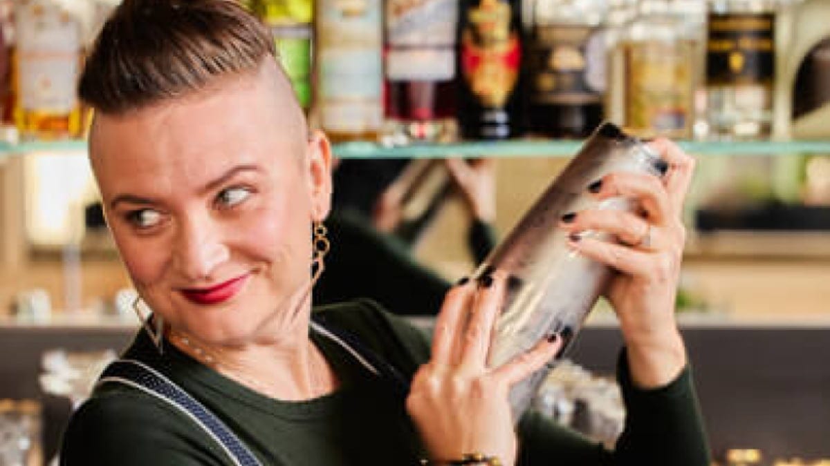 A bartender shakes a cocktail during a hands-on indoor mixology team building class in the Bay Area