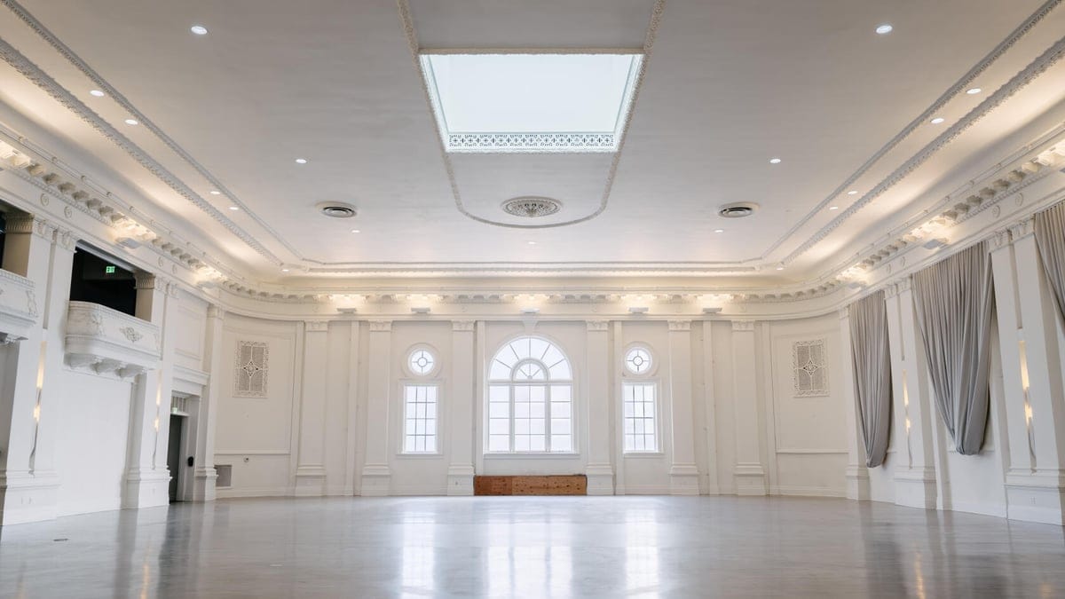 White ballroom event venue in San Francisco with arched windows, stage, and skylight