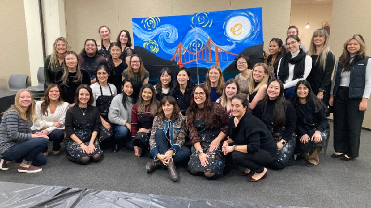 Corporate team posing with the finished bridge mural they painted together at a Peninsula team building workshop