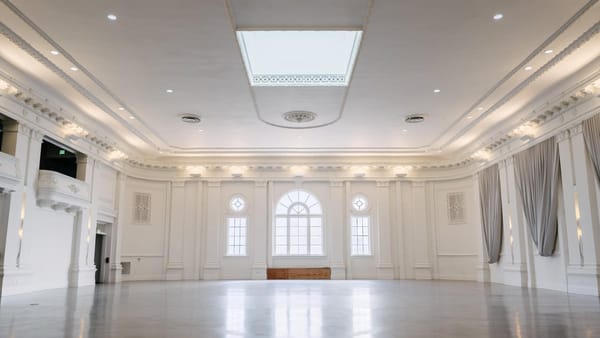 White ballroom event venue in San Francisco with arched windows, stage, and skylight